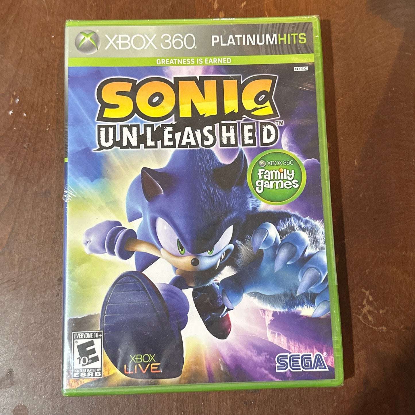 Sonic Unleashed game case on a wooden surface with a mouse and other items.