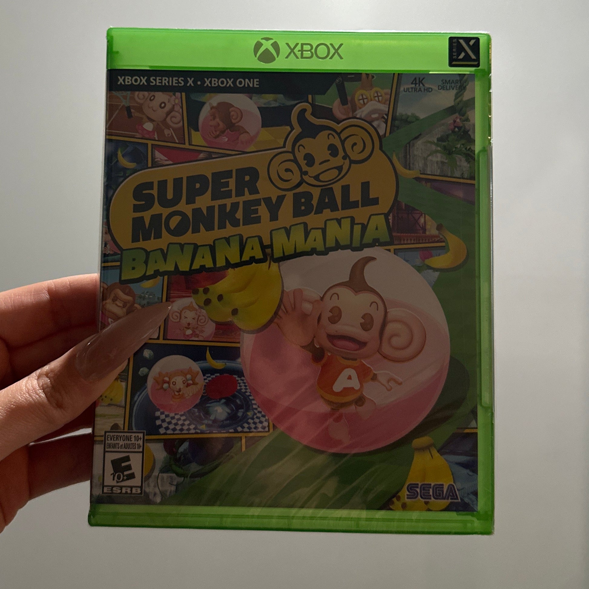 Hand holding a 'Super Monkey Ball' game case against a white background
