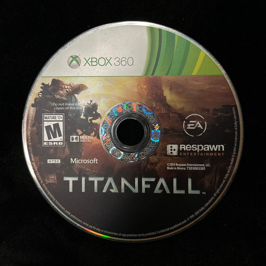A used Xbox 360 game disc for Titanfall, featuring the game's cover art and logos for Xbox 360, Microsoft, EA, and Respawn, resting on a black surface.