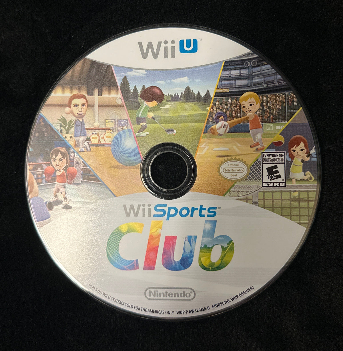 A Wii Sports Club video game disc for the Nintendo Wii U, resting on a black fabric surface. The disc features colorful illustrations of characters playing sports and the game title 'Wii Sports Club' with the Nintendo logo at the bottom.
