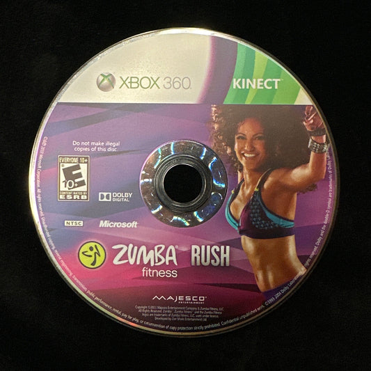 A used Xbox 360 Kinect Zumba Rush fitness game disc resting on a black fabric surface.